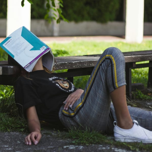 a kid lying on the ground with a book over their face
